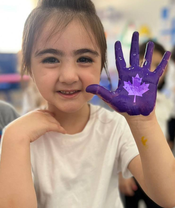 A CIS student showing a painted maple-leaf handprint